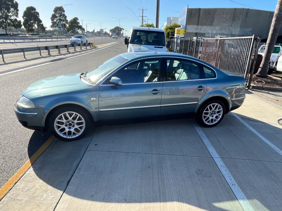 Silver car parked on the side of a road with a clear sky
