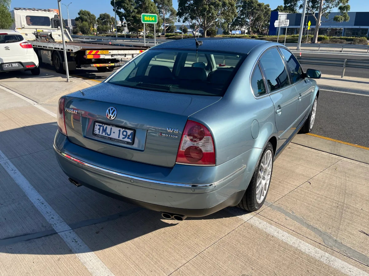 Blue Volkswagen car parked on a road with a truck in the background