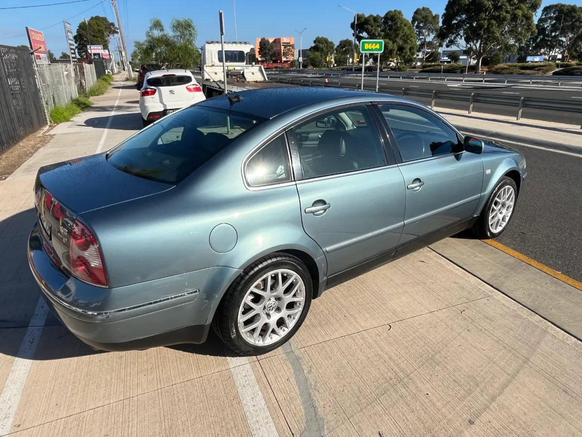 Blue sedan car parked on a roadside with a clear sky
