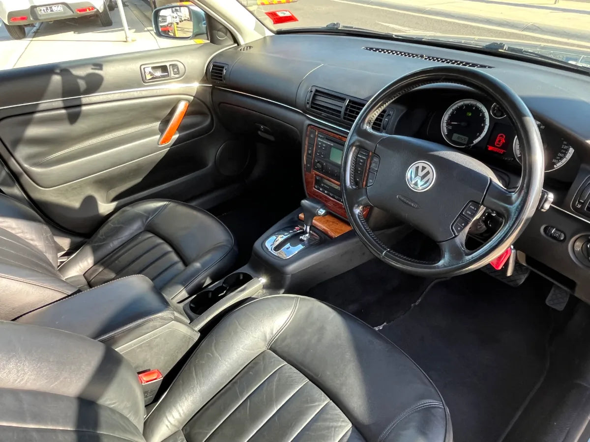 Car interior with steering wheel and dashboard, featuring a Volkswagen logo.