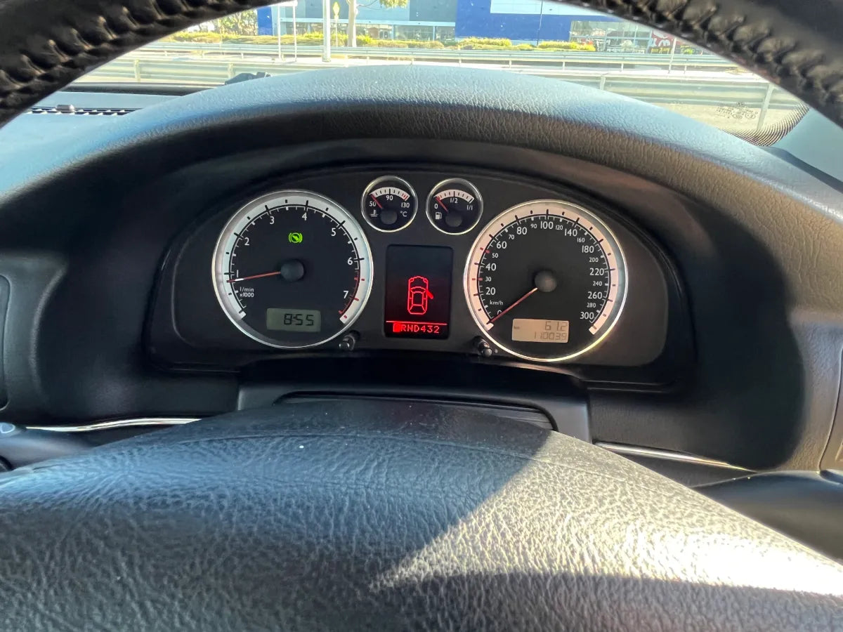 Car dashboard with speedometer and tachometer, showing a warning light.