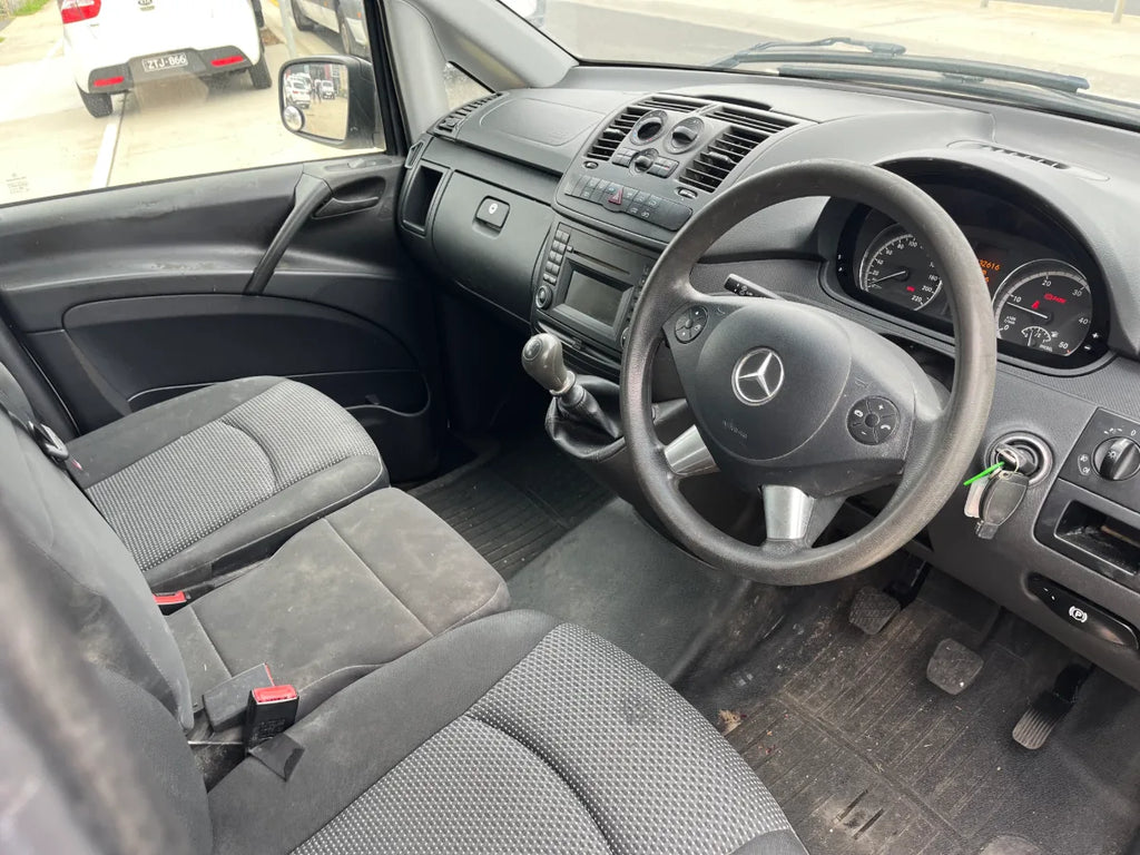 Car interior with steering wheel and dashboard, showing Mercedes-Benz logo.