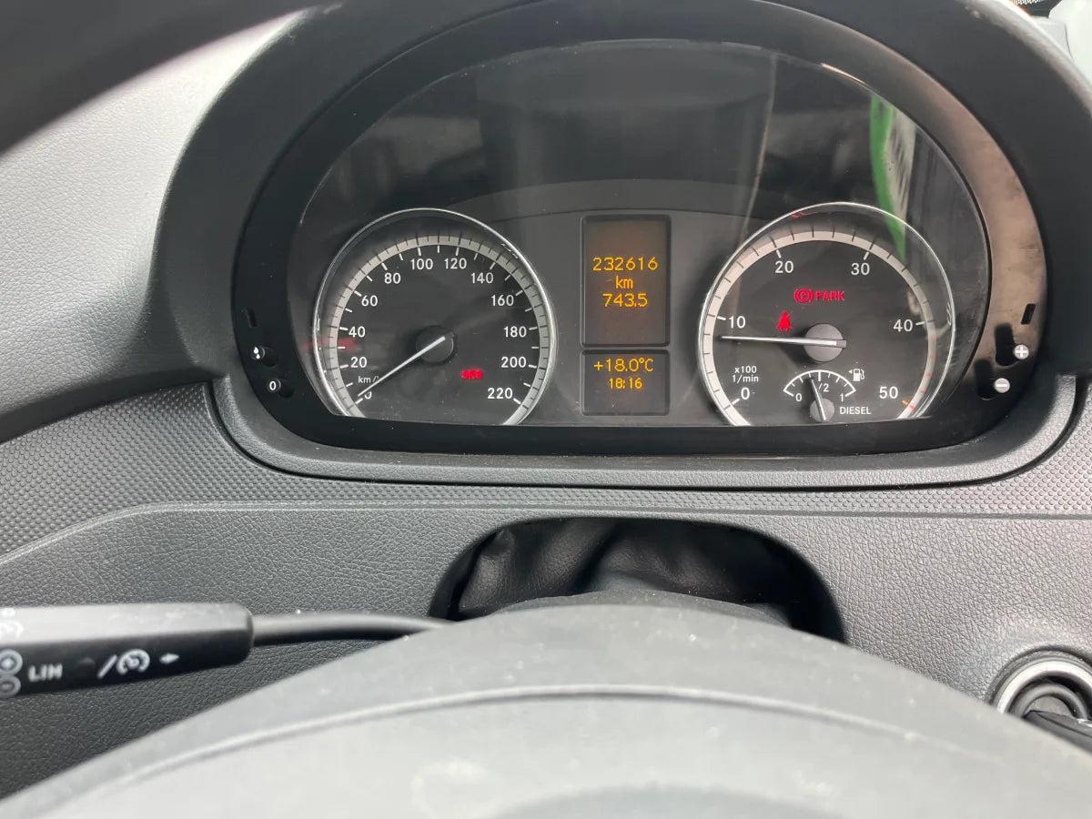 Car dashboard with speedometer and digital display showing various metrics.