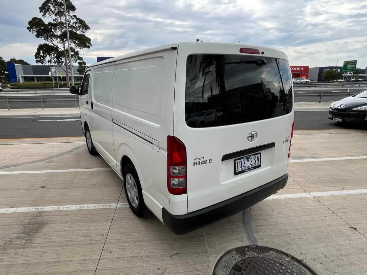 White van parked on a concrete surface with a cloudy sky in the background