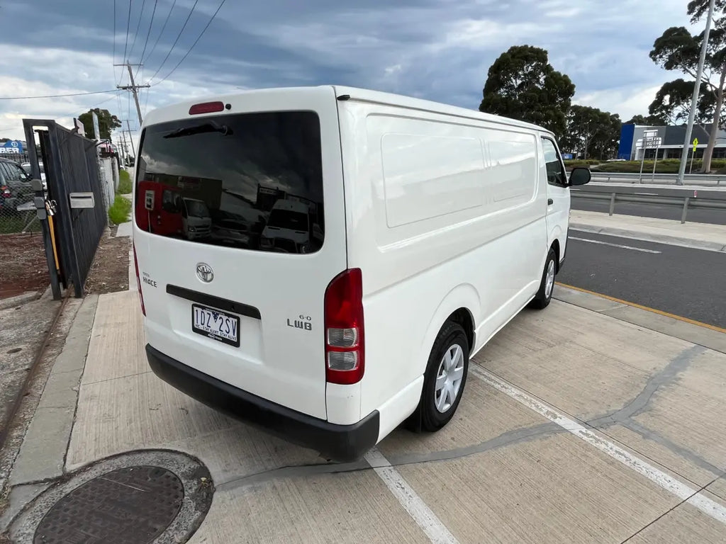 White van parked on a street with trees and power lines in the background
