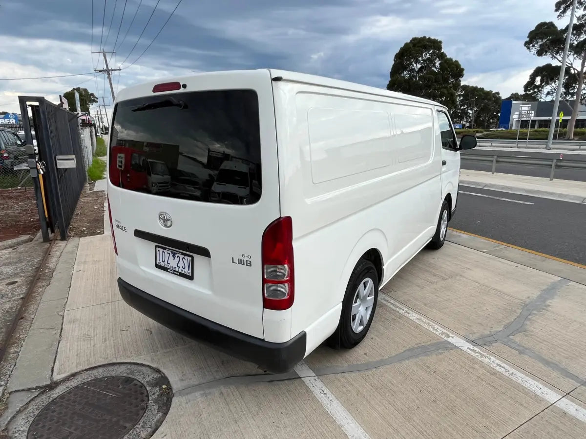 White van parked on a street with trees and power lines in the background
