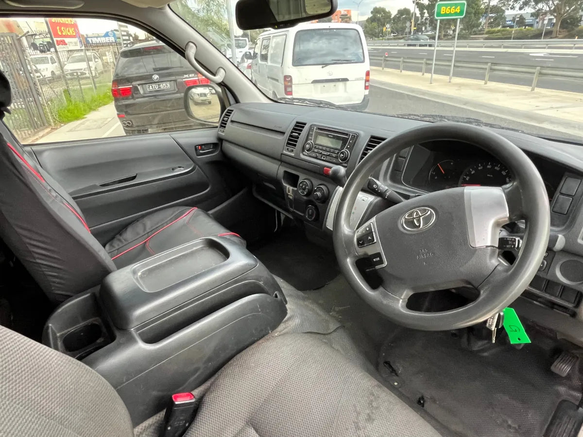 Car interior with steering wheel and dashboard, showing a Toyota logo.