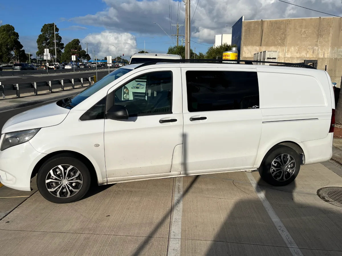 White van parked on a concrete surface with a road and buildings in the background