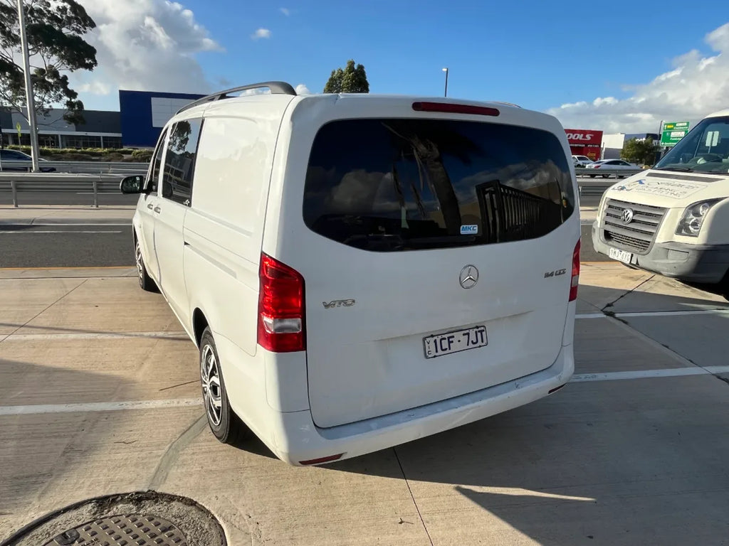 White Mercedes-Benz van parked on a concrete surface with a clear sky in the background.