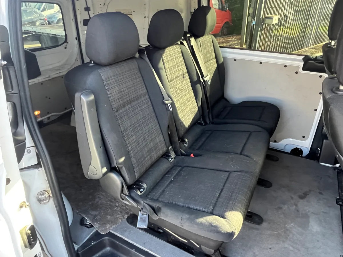 Back seat of a vehicle with gray upholstery and visible wear, showing signs of use.