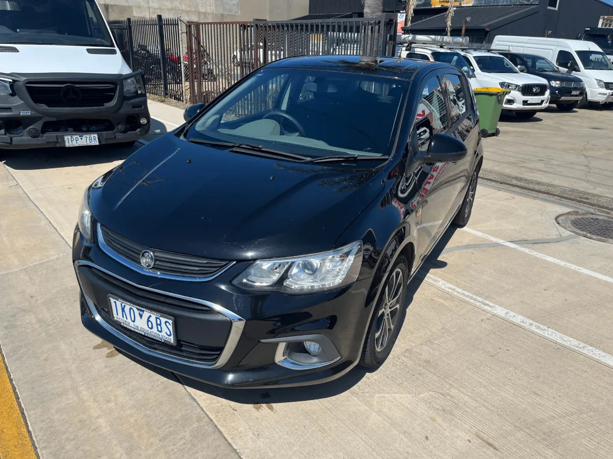 Black car parked in a parking lot with other vehicles in the background
