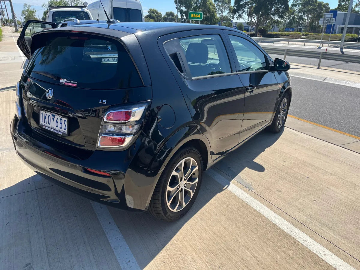 Black car parked on a road with a clear sky background